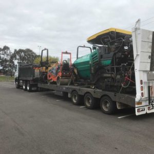 Tri Axle With Bifold Ramps Loaded With Asphalt Equipment